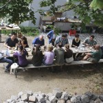 Circa 20 Menschen an Bierbänken, essend.