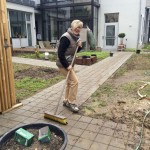 Eine Frau kehrt einen Gartenweg